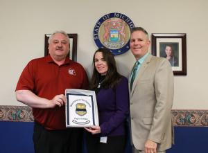 Tom Tylutki, left, presents the Flag for the Fallen to MDOC Director Heidi Washington and Macomb Warden Randall Haas.